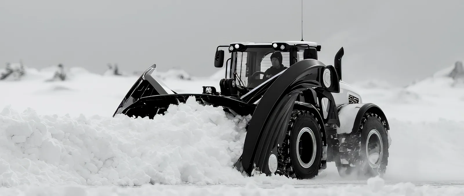 Wheel loader with a front blade pushing a deep pile of snow, flat overcast light.